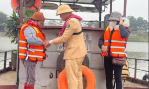 Cán bộ cảnh sát giao thông hướng dẫn người dân tham gia giao thông đường thủy mặc áo phao.