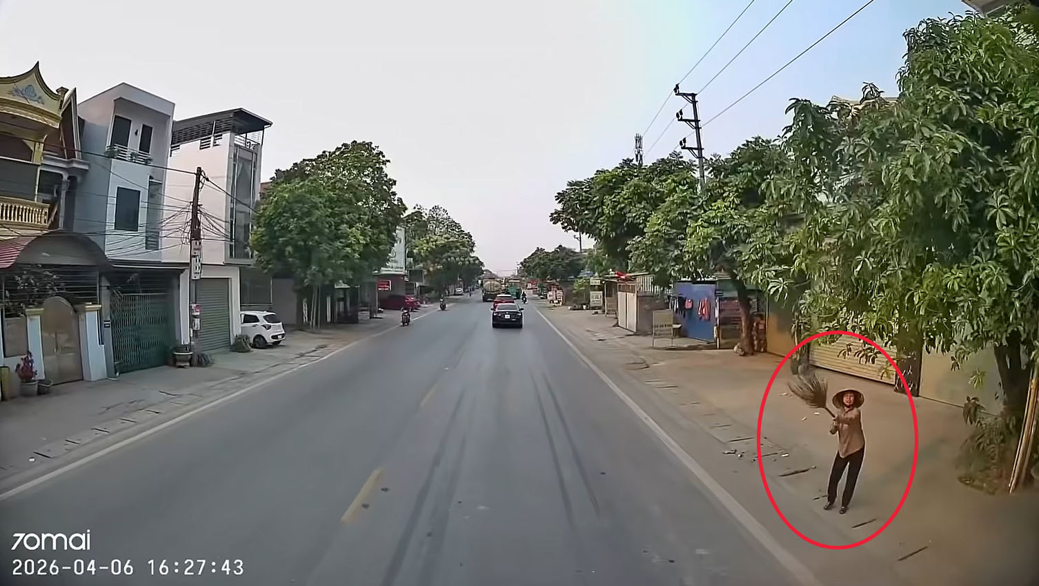 Người phụ nữ bên đường giơ chiếc chổi lên ra hiệu thì xe tải mới dừng lại.